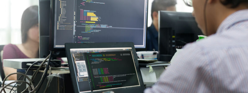 55430647 - asian outsource developer looking screen sitting at desk working laptop computer mobile application software real office